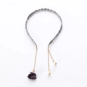 Detail of grey pleated headband featuring golden chains with purple flowers and pearls