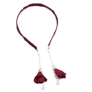 Detail of dark red pleated headband featuring silver chains with flower tassels and pearls