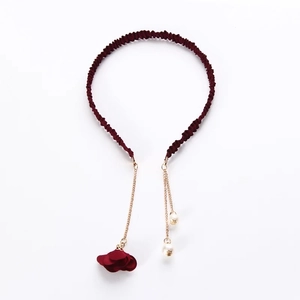 Detail of red fabric headband with gold chains, cloth flowers and white pearls