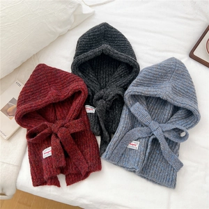 Detail of ribbed knit hooded scarves in red, black, and blue with drawstring closure