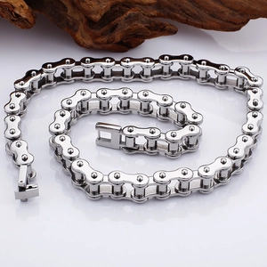 Polished silver motorcycle chain necklace on reflective surface with driftwood