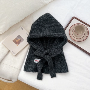 Detail of grey knitted balaclava with decorative drawstring on a soft white background