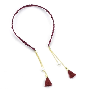 Detail view of burgundy fabric headband with gold chain tassels and pearl accents