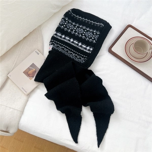 Flat lay of a black knit balaclava scarf with Nordic jacquard pattern on a cozy background