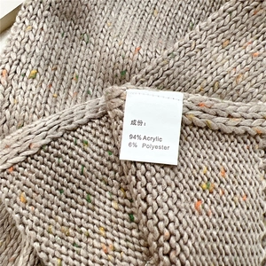 Makrodetail aus weichem Noppengarn-Strickschal mit Materialstruktur und Pflegeetikett