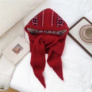 Detail of red jacquard knitted hooded scarf with vintage pattern for winter warmth