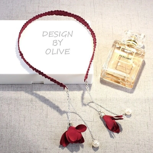 Detail of wine red fabric headband with hanging metal chains, pearls, and cloth flowers