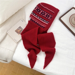 Detail view of red knitted hooded scarf with blue and white Fair Isle geometric pattern