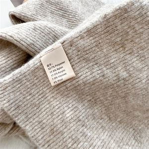 Close-up of knit scarf material label showing wool blend composition and soft texture