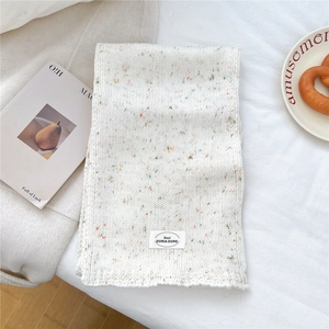 Nahaufnahme des beigen Strickschals mit Konfetti-Muster und gewebtem Etikett-Detail