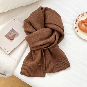 Close-up of brown knitted scarf featuring a leather label and ribbed texture detail