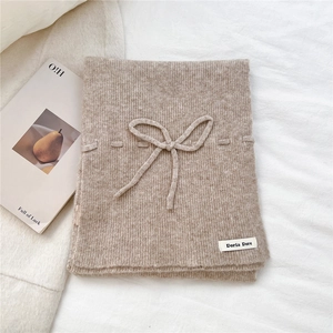 Detailed knit texture of beige bow neck warmer on soft fabric background