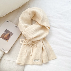 Close-up of beige knitted scarf featuring vertical stripes and a bow tie detail