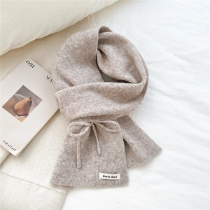 Macro detail of oatmeal knit scarf featuring soft ribbed texture and bow drawstring detail
