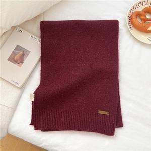 Detailed view of dark burgundy knit scarf featuring ribbed edges and a premium leather label