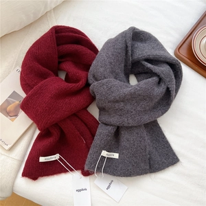 Thick wool blend knitted scarf in burgundy and dark grey on a cozy home setting