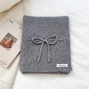 Close-up of dark grey knitted scarf with ribbed texture and decorative bow detail