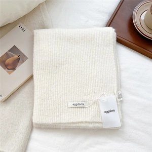 Detail of cream wool knit scarf texture with brand tag and 45% wool fiber composition