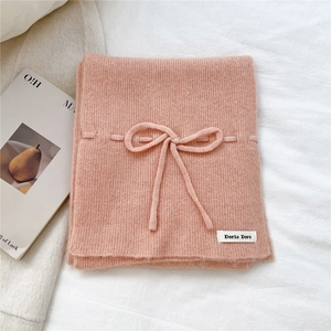 Close-up of soft peach knitted scarf with a matching bow tie and branded fabric label