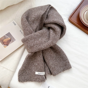 Macro detail of dark brown wool knit scarf with brand label on a cozy background