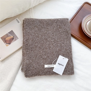 Close-up of brown wool blend knit scarf texture with soft ribbed pattern on white fabric