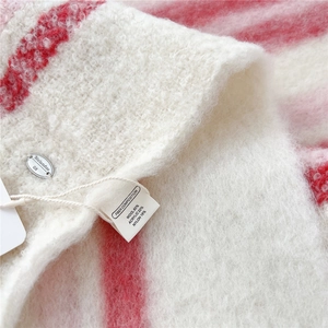 Detailed close-up of wool blend scarf texture with metal logo and material tag