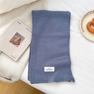 Detaillierte Textur des dunkelblauen Strickschals mit dekorativem Markenetikett