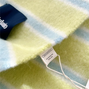 Detail of wool blend striped scarf showing material label and soft knit texture