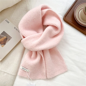 Close-up of soft pink knitted wool scarf with detailed ribbed texture on a white background