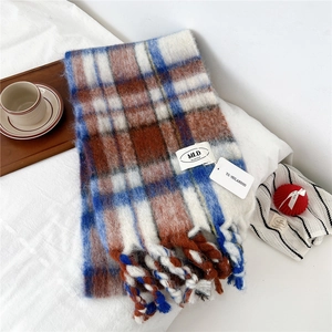 Detailed close-up of striped knit scarf with blue, white, and caramel plaid fringe detail