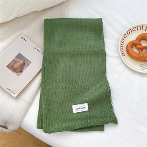 Detailaufnahme des grünen Strickschals mit bunten Tupfen und gerippter Textur