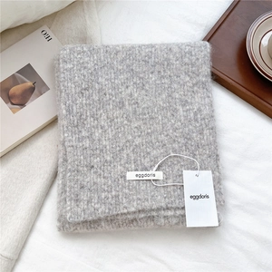 Close-up of soft grey wool blend knitted scarf texture with minimalist brand label