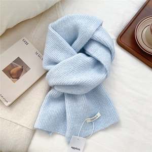 Detail of soft blue wool knit scarf with thick ribbed texture and premium woven label