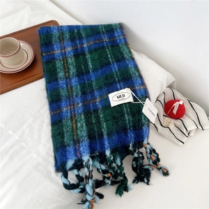 Detail of striped tassel scarf with navy and green plaid texture on white soft fabric