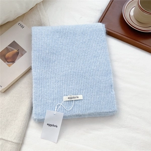 Close-up of light blue wool knit scarf showing ribbed texture and brand tag