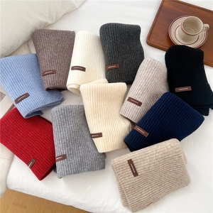 Detailed knit texture and leather brand label on thick ribbed winter scarves