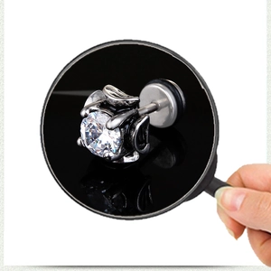 Vintage silver stud earring with clear zircon under magnifying glass on white background