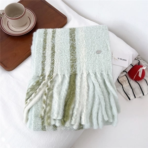 Close-up of soft wool striped scarf with thick tassels and silver metal logo tag