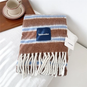 Detail of wool blend striped scarf with tassels on white linen and coffee cup