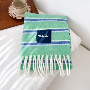 Detailed knit texture of light green striped scarf with white tassels and brand label