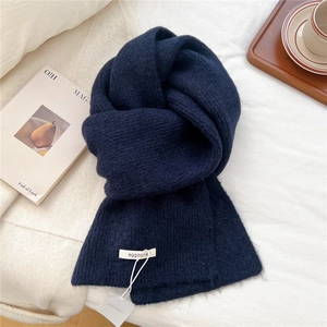 Detailed texture of thick dark blue wool knit scarf with brand label on a cozy setting