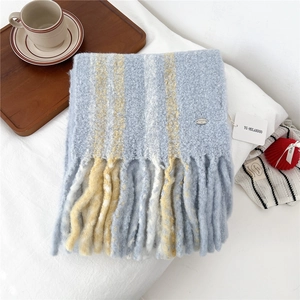 Detail of soft striped wool scarf with chunky tassels and brand tag on white fabric