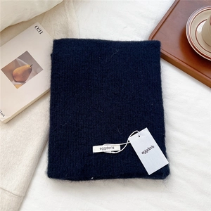 Detailed close-up of dark blue knit wool scarf texture on a warm wooden aesthetic tray