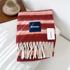Close-up of striped wool scarf with colorful fringe and brand label on white fabric