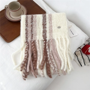 Close-up of thick striped wool scarf with long tassels and soft knit texture on bed