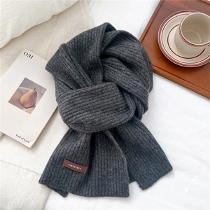 Detail of dark grey knit scarf with vertical rib pattern and premium leather logo patch
