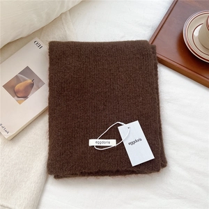 Detail of coffee brown wool knit scarf texture with brand tag on a cozy tray