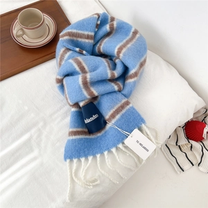 Detail of striped wool scarf with long white fringe and brand tags on white bedding