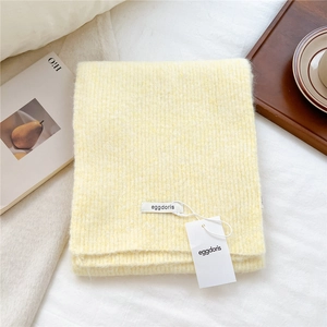 Close-up of soft beige wool knit scarf with ribbed texture and brand labels