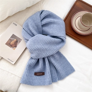 Detailed macro view of light blue ribbed knit scarf with a brown rectangular brand tag